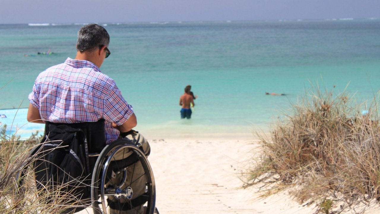 Ein Mensch in einem Rollstuhl am Strand.