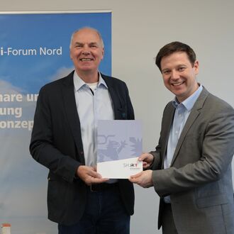 Arbeitsstaatssekretär Tobias von der Heide überreicht Geschäftsführer Thies Bielenberg den Zuwendungsbescheid.